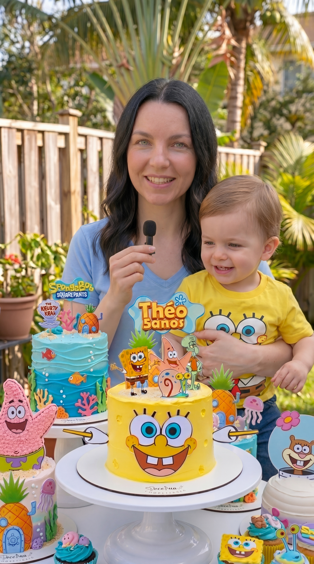 Juliana Cardoso segurando seu filho ao lado da mesa de festa temática que ela mesma montou